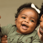 Mom and Dad smiling and holding happy baby