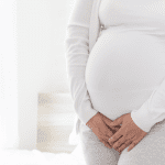 Pregnant woman holding herself due to lightning crotch pain