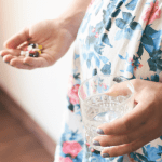 Pregnant woman holding vitamins and glass of water