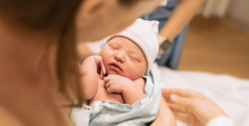 pregnant woman holding newborn baby after giving birth to symbolize best baby names for new moms