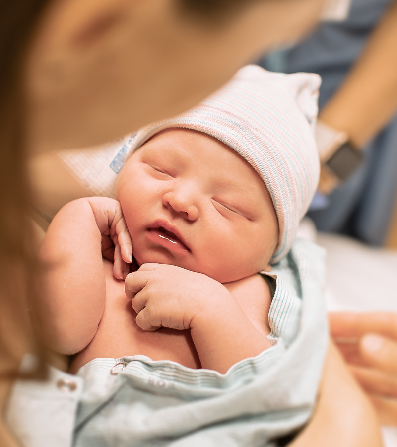 pregnant woman holding newborn baby after giving birth to symbolize best baby names for new moms